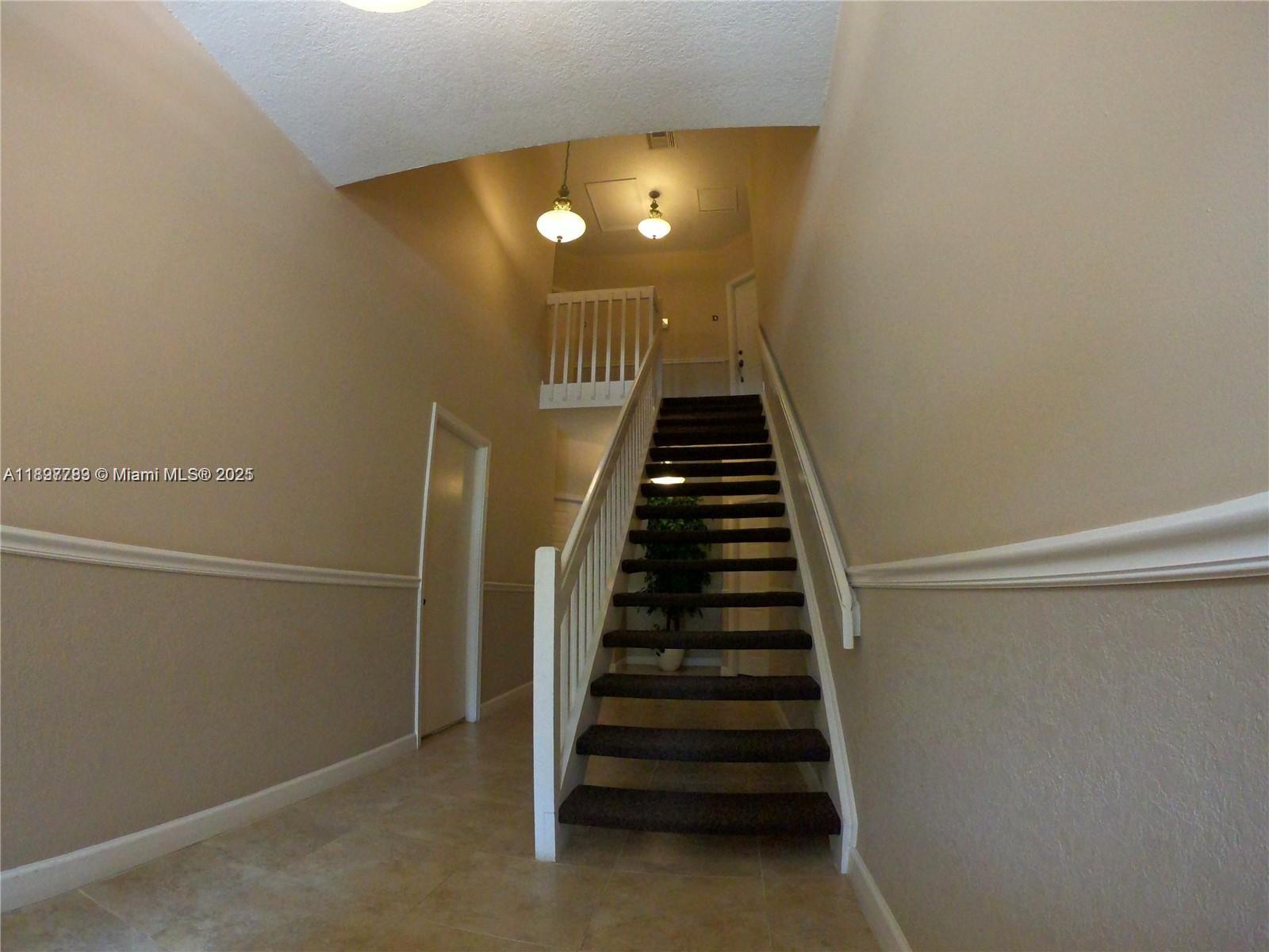 A staircase with dark carpet and white railings leads to an upper landing — 5800 Coach House Cir, Boca Raton FL 33486, BOCA RATON, FL