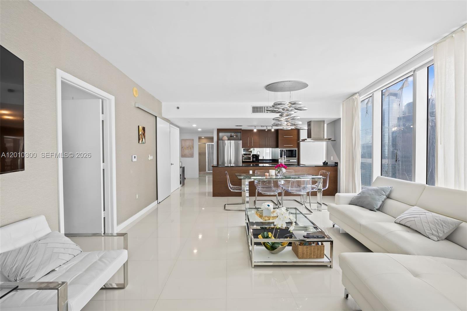 This open-concept living and dining area features white tile floors, modern furniture, and a kitchen — 495 Brickell Ave # 3710, Miami FL 33131, MIAMI, FL