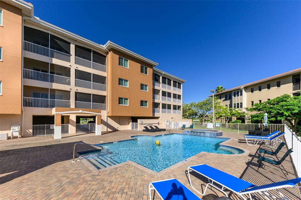 A swimming pool sits in front of a multi-story apartment building with screened balconies — 3322 PURPLE MARTIN DRIVE UNIT 135, PUNTA GORDA, FL