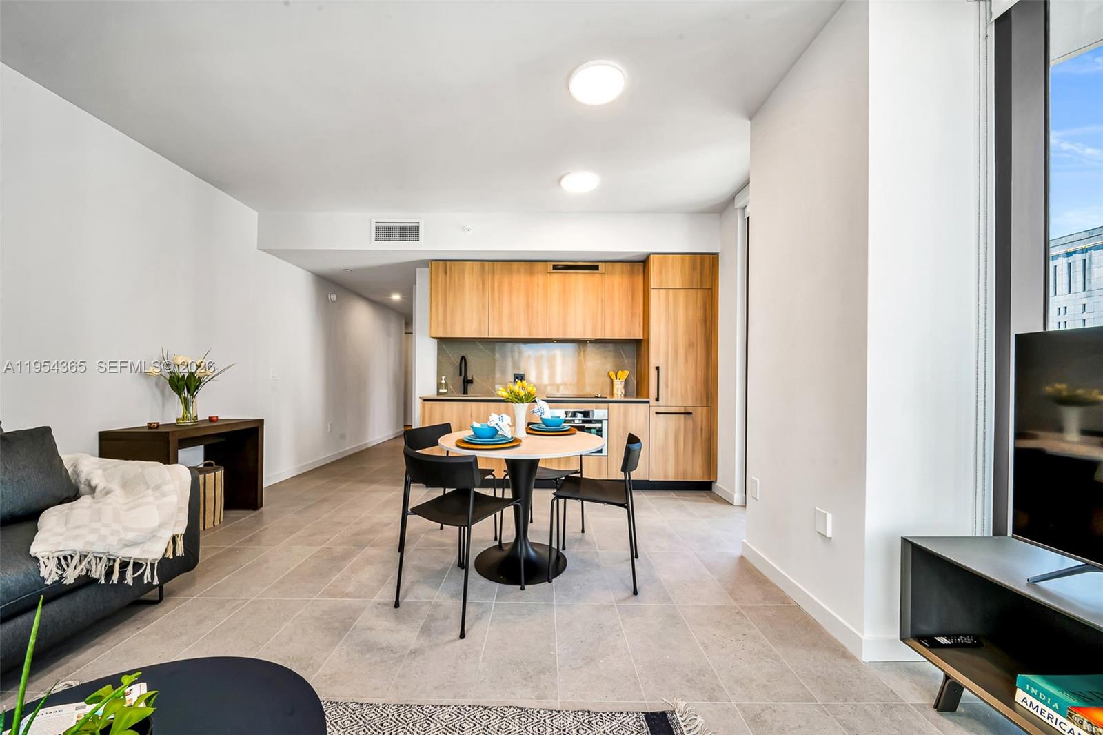 A modern open-concept living area features light wood cabinetry, tile flooring, and a dining table — 121 NE 5th St # 1608, Miami FL 33143, MIAMI, FL