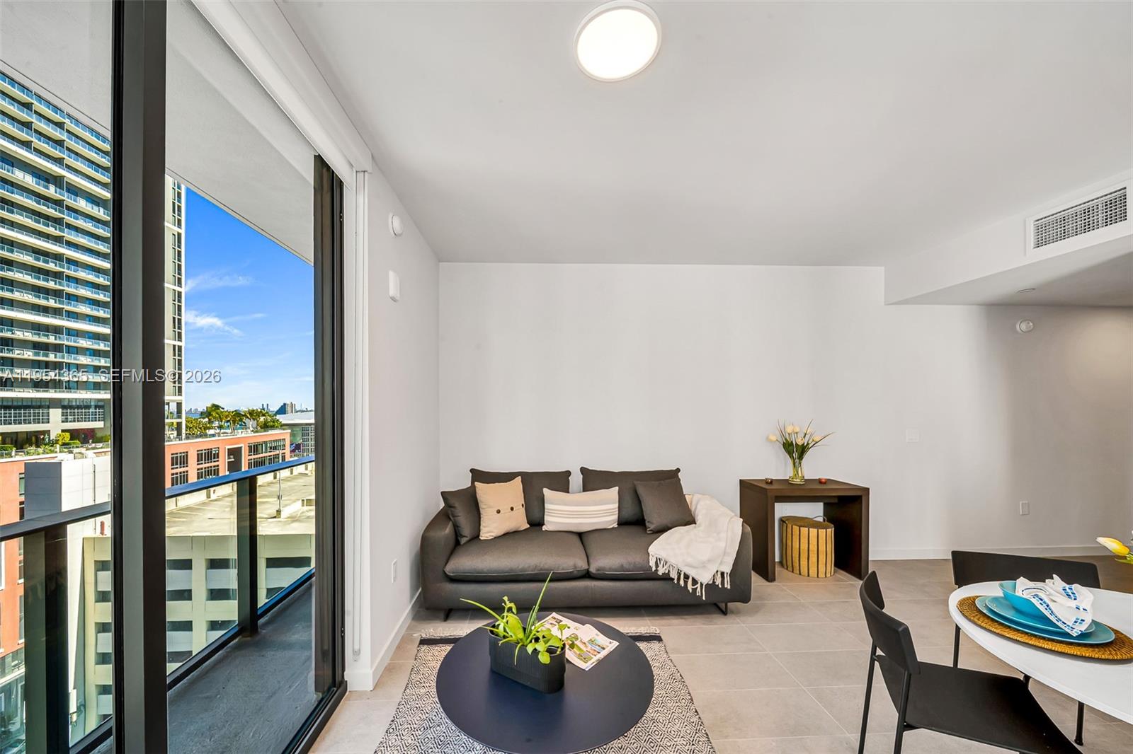 A living room features a dark sofa, a round coffee table, and a balcony view — 121 NE 5th St # 1608, Miami FL 33143, MIAMI, FL
