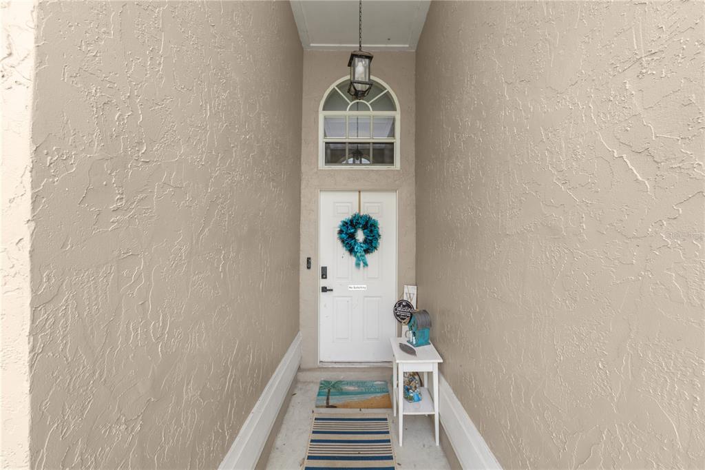 A covered entryway features a white front door with a wreath, a transom window, and decor — 6201 VINTAGE DRIVE, LAKELAND, FL