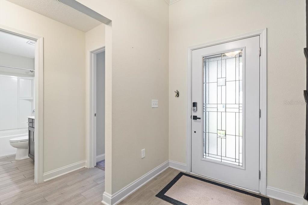 An entryway with light-colored flooring, a white front door with glass, and an adjacent bathroom — 27 COLORADO SPRINGS WAY, ST AUGUSTINE, FL