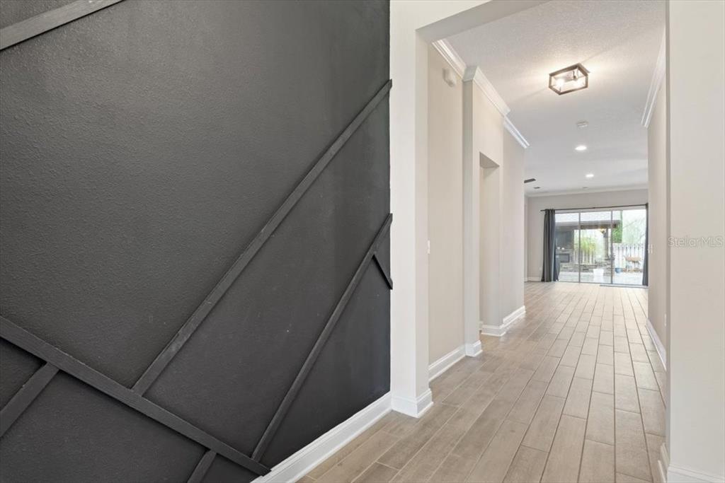 A hallway with a black accent wall leads to an open living area with tile flooring — 27 COLORADO SPRINGS WAY, ST AUGUSTINE, FL