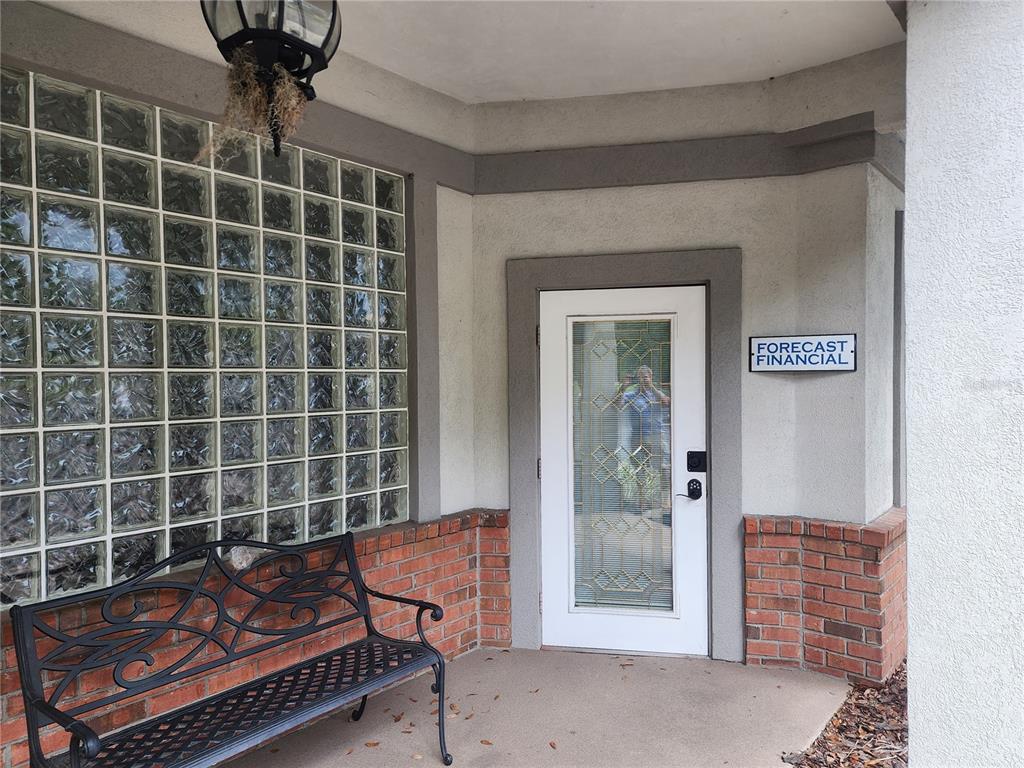 A building entrance features a glass block wall, a white door, and a black metal bench — 101 NW 75TH STREET UNIT Suite 1-A, GAINESVILLE, FL