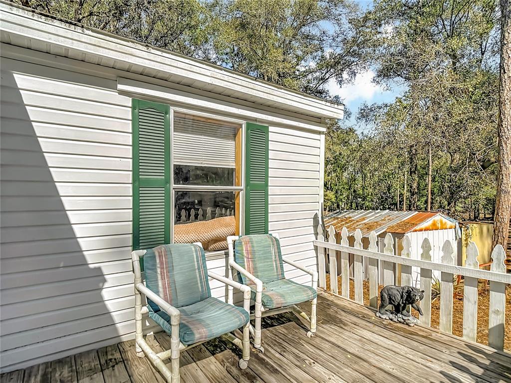 Two chairs sit on a wooden deck outside a house with white siding — 6421 SUNNYSIDE RANCH ROAD, BROOKSVILLE, FL