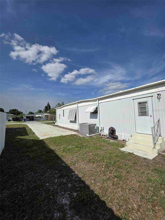 The exterior side of a mobile home features a concrete driveway, HVAC unit, and stairs — 3217 ILLINOIS AVENUE, SEBRING, FL