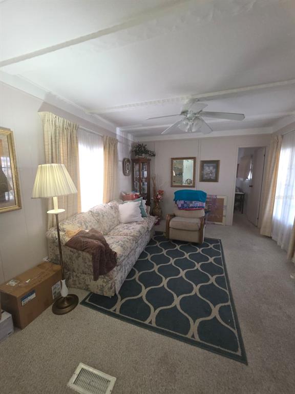 A living room features a floral sofa, a patterned area rug, and a ceiling fan — 3217 ILLINOIS AVENUE, SEBRING, FL
