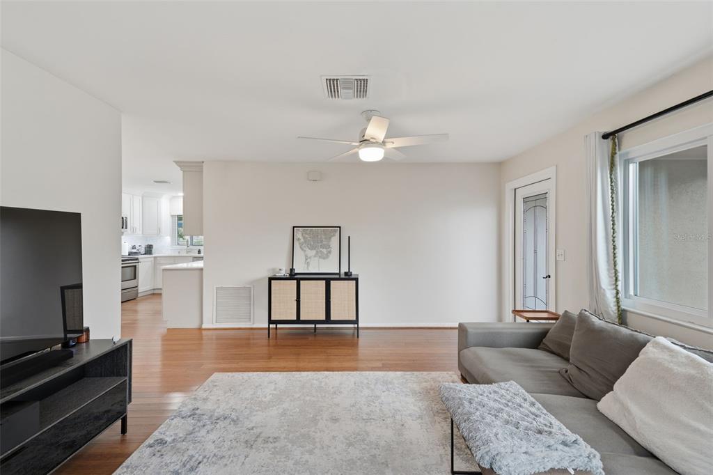 A living room features hardwood floors, a gray sectional sofa, and a black console table — 205 SE MONROE CIRCLE N, ST PETERSBURG, FL