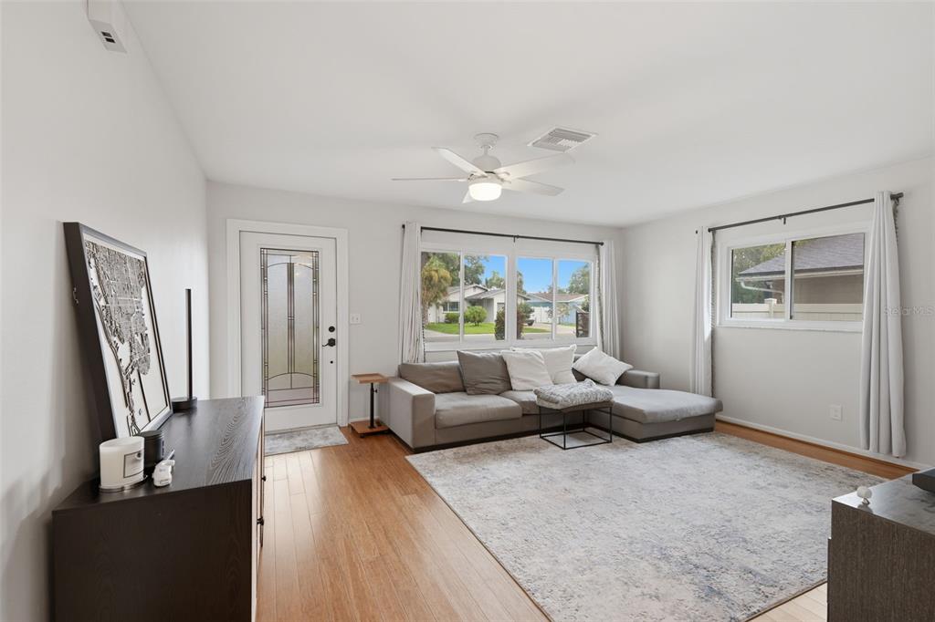 A living room features a gray sectional sofa, a large area rug, and hardwood floors — 205 SE MONROE CIRCLE N, ST PETERSBURG, FL
