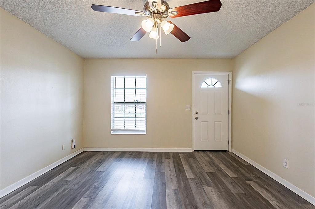 An empty room features light-colored walls, a ceiling fan, a window, and wood-look flooring — 8528 GOLD RIDGE CIRCLE, TAMPA, FL