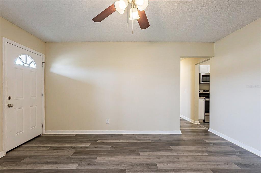 An empty room with light-colored walls, a ceiling fan, and gray wood-look flooring — 8528 GOLD RIDGE CIRCLE, TAMPA, FL