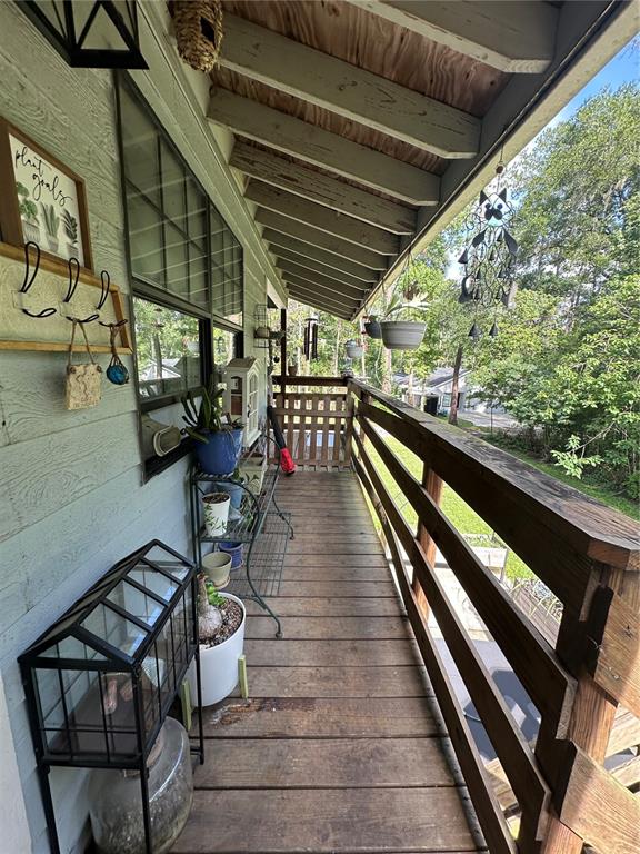 A wooden balcony features a railing, potted plants, a small greenhouse, and a wall-mounted rack — 7035 SE 23RD COURT, OCALA, FL
