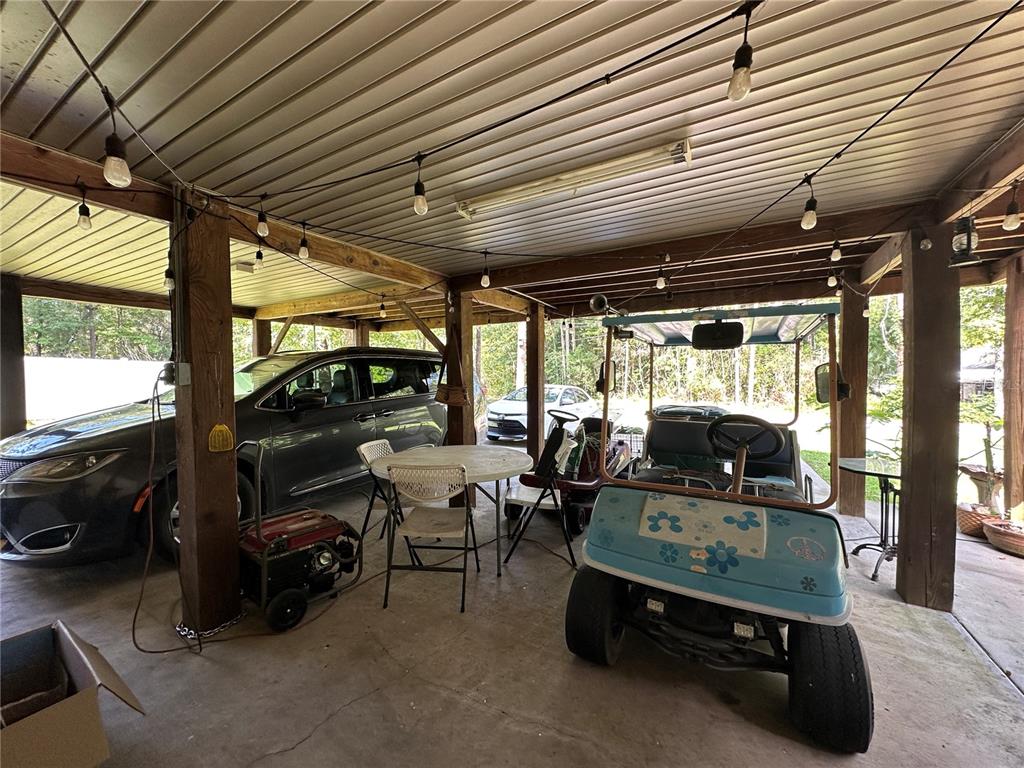 A covered outdoor carport area features a parked car, a golf cart, and patio furniture — 7035 SE 23RD COURT, OCALA, FL