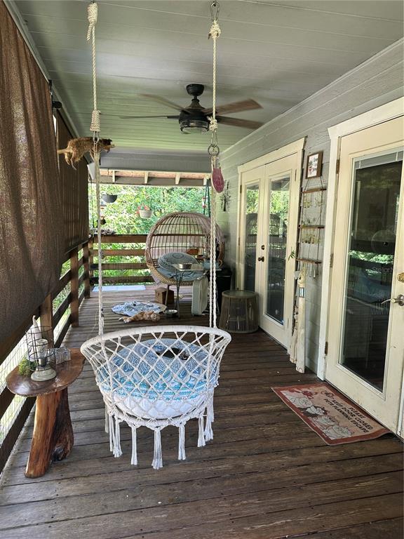 A covered wooden porch features a hanging macramé chair, a ceiling fan, and glass doors — 7035 SE 23RD COURT, OCALA, FL