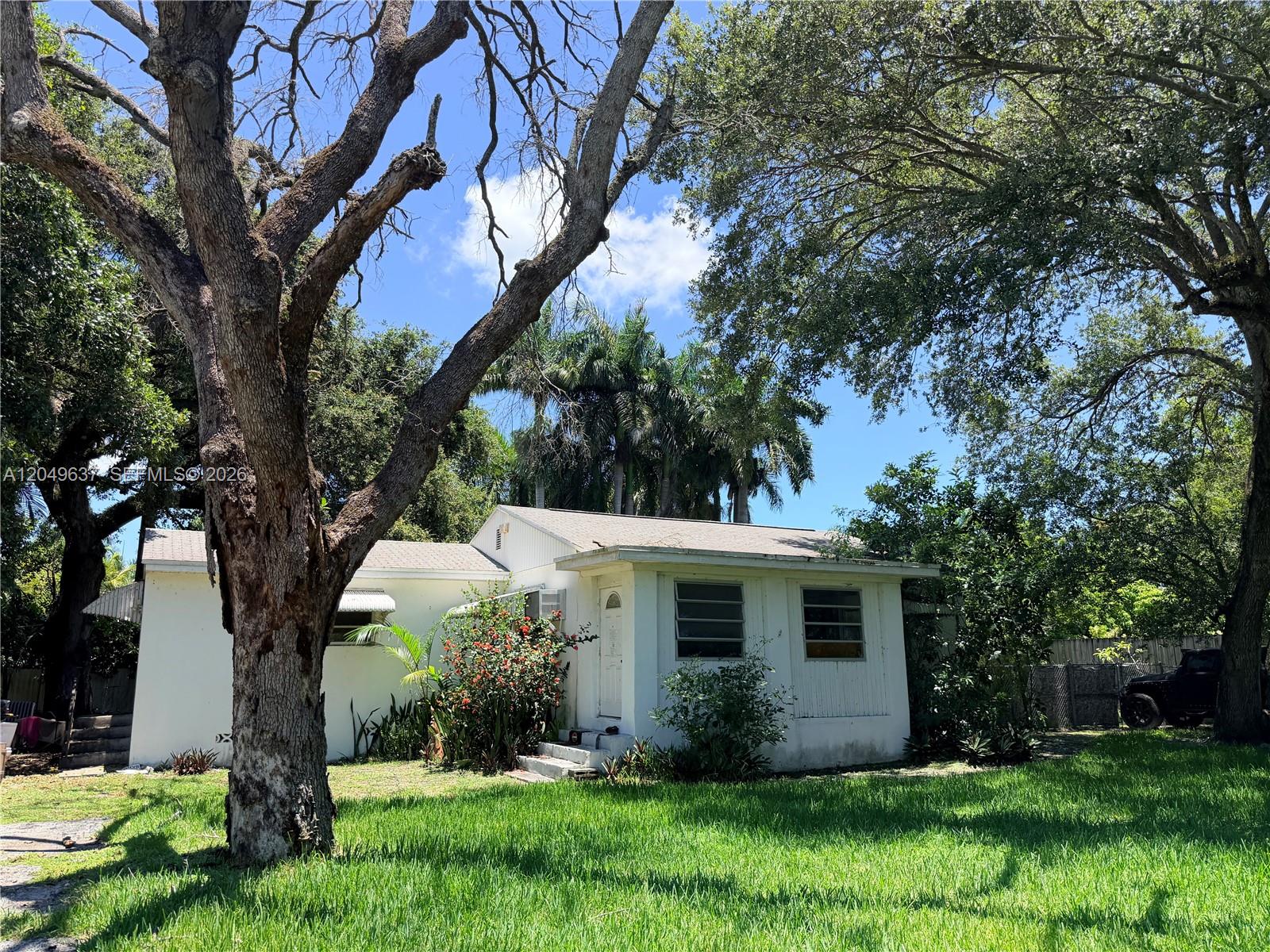 A single-story white house with a gabled roof sits behind a large tree — 479 NE 151st St, Miami FL 33162, MIAMI, FL