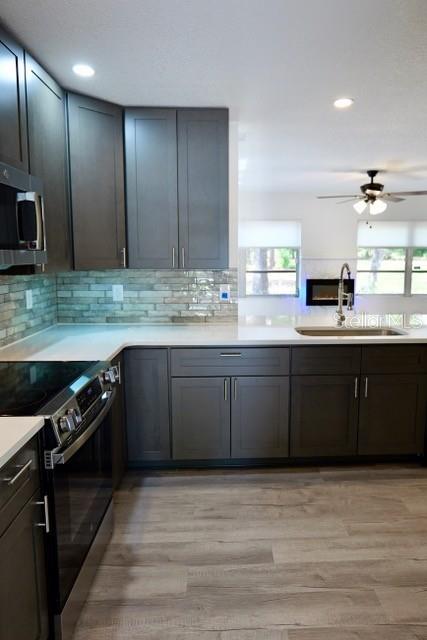 A modern kitchen features dark gray cabinetry, light countertops, and wood-look flooring — 9120 SW 210TH CIRCLE, DUNNELLON, FL
