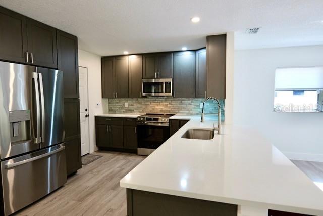 A modern kitchen features dark cabinetry, stainless steel appliances, and a white quartz island countertop — 9120 SW 210TH CIRCLE, DUNNELLON, FL