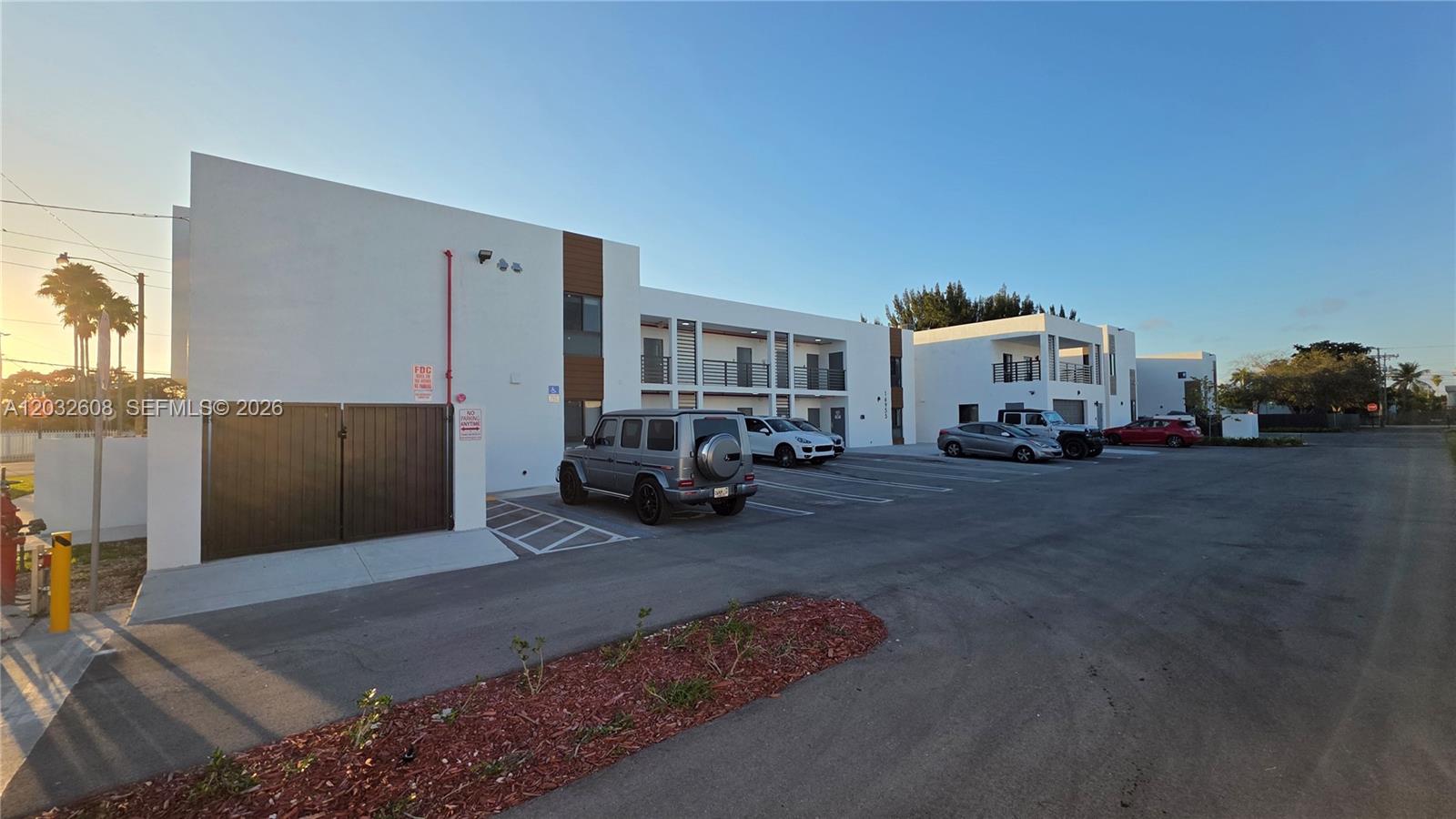 An exterior view of a modern apartment building with a parking lot in front — 16955 SW 100th Ave # 1, Miami FL 33157, MIAMI, FL