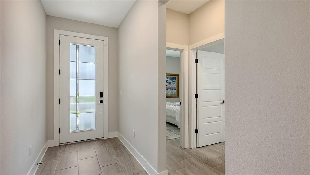 An entryway features a white front door with glass panels and light-colored wood-look tile flooring — 491 DAYLILY BOULEVARD, NOKOMIS, FL