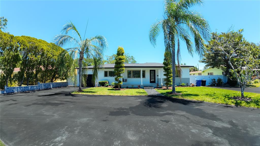 A single-story house with a large asphalt driveway, palm trees, and a manicured lawn — 936 ALCAZAR WAY S, ST PETERSBURG, FL
