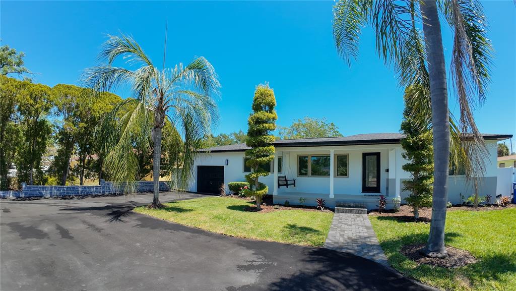 A single-story house with a white exterior, a paved walkway, and a large asphalt driveway — 936 ALCAZAR WAY S, ST PETERSBURG, FL