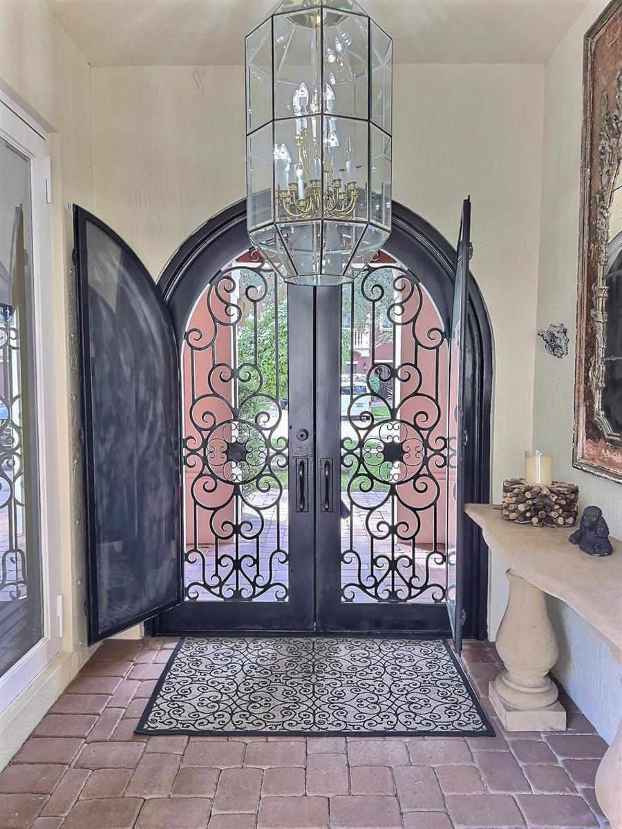 An arched double iron door entry features a large glass lantern pendant light — 9183 Nugent Trail, West Palm Beach FL 33411, WEST PALM BEACH, FL
