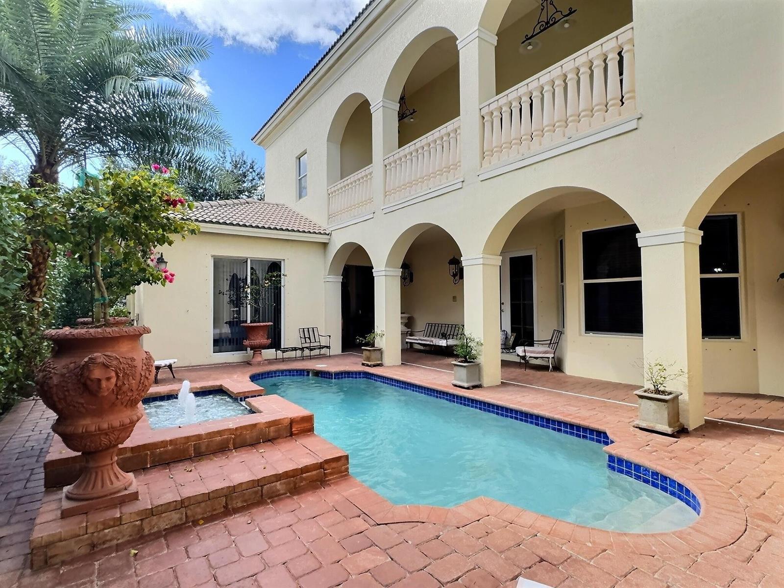 A two-story house with a pool, fountain, and arched patio overlooks a brick-paved courtyard — 9183 Nugent Trail, West Palm Beach FL 33411, WEST PALM BEACH, FL