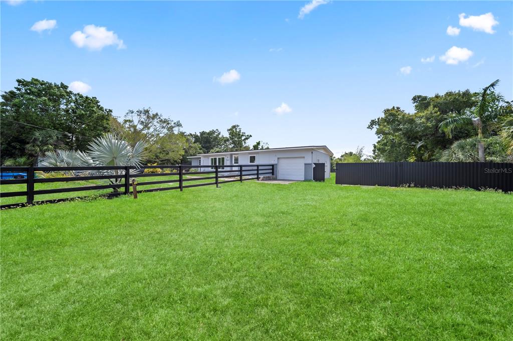 A single-story house with a garage sits behind a black fence in a grassy yard — 1507 LAVILLA ROAD, PUNTA GORDA, FL