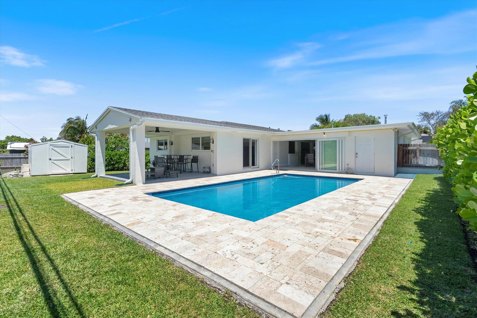 A backyard features a rectangular swimming pool, a stone patio, and a covered outdoor seating area — 108 SE 31st Avenue, Boynton Beach FL 33435, BOYNTON BEACH, FL