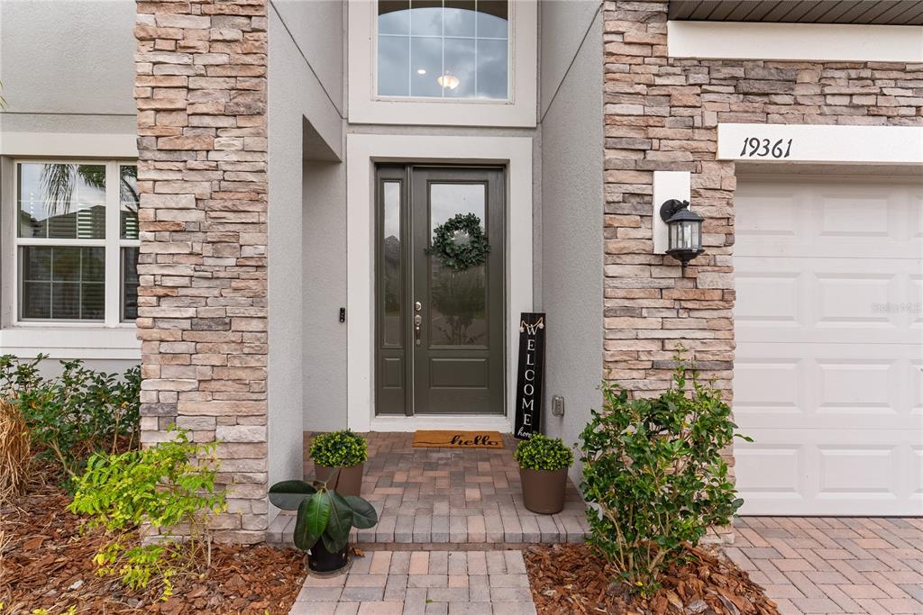 The exterior entrance features a stone-veneer facade, a dark front door, and a paved walkway — 19361 EAGLE CREEK LANE, TAMPA, FL