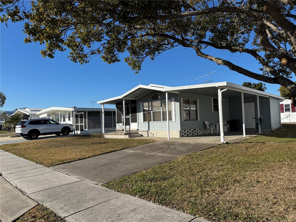 A light blue manufactured home with a concrete driveway and a covered carport — 35170 DANNY DRIVE UNIT 159, ZEPHYRHILLS, FL