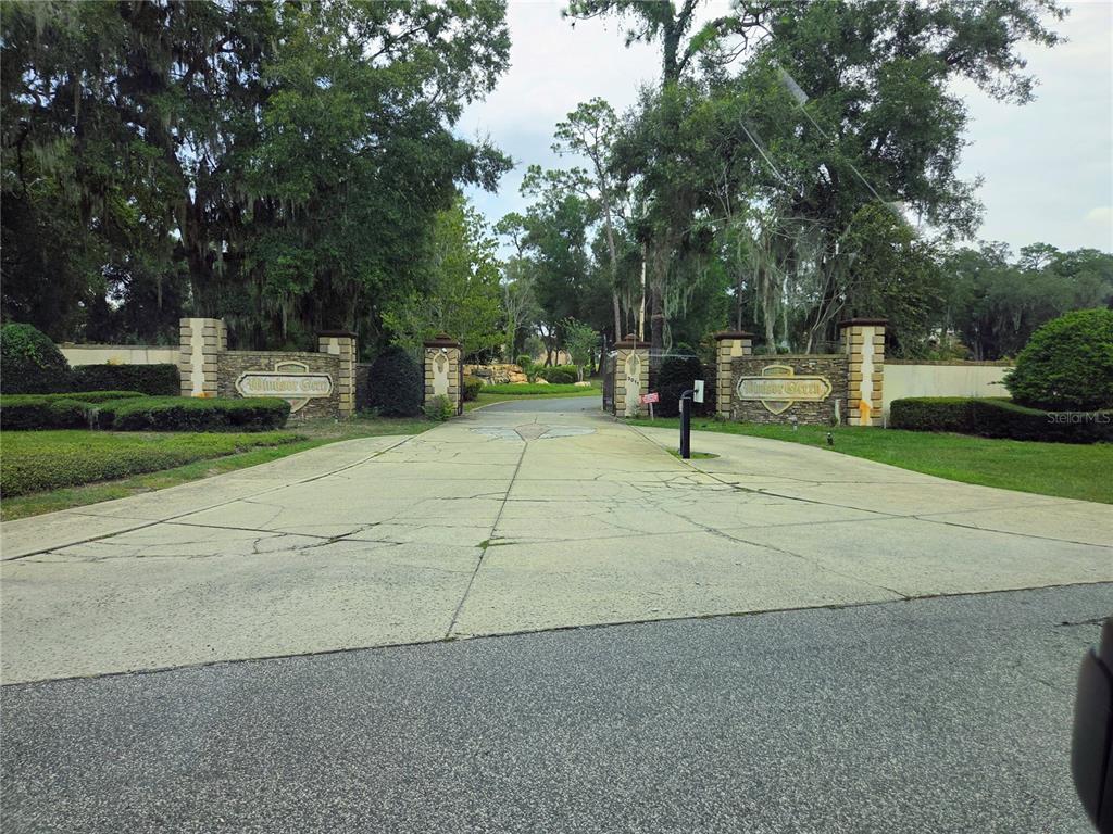 A gated entrance with stone pillars and signage leads into a tree-lined residential community — 000 DARLINGTON AVENUE, LADY LAKE, FL