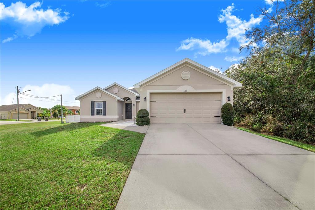 A single-story house with a beige stucco exterior, a two-car garage, and a concrete driveway — 230 GROUPER COURT, POINCIANA, FL