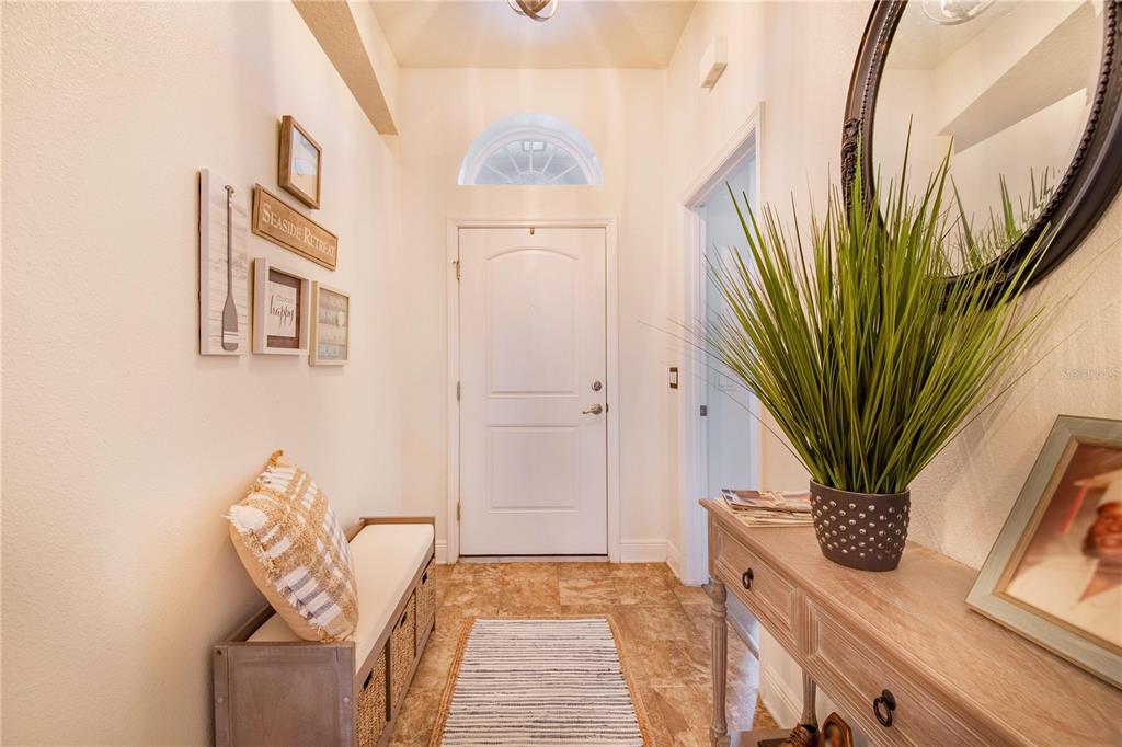 An entryway features a bench, a console table with a plant, and wall-mounted coastal decor — 230 GROUPER COURT, POINCIANA, FL