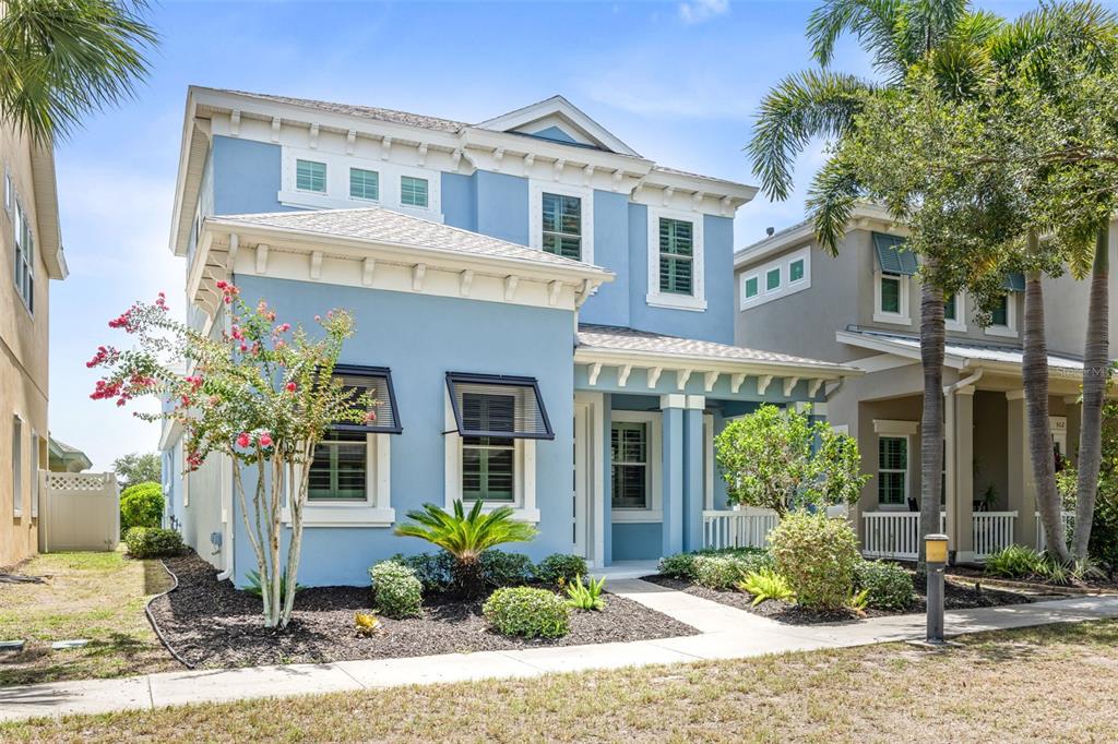 A two-story light blue house with a front porch and dark window awnings — 510 WINTERSIDE DRIVE, APOLLO BEACH, FL