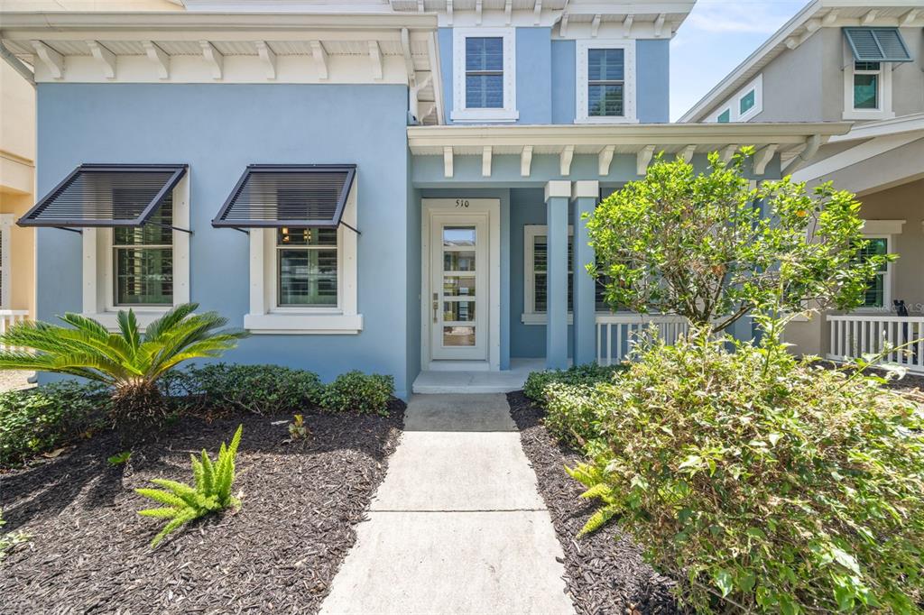 A light blue two-story house features a front walkway, a glass-paneled door, and window awnings — 510 WINTERSIDE DRIVE, APOLLO BEACH, FL