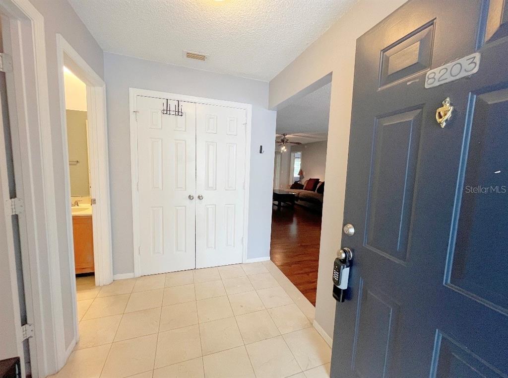 An entryway with tiled floors, a dark blue front door, and white double closet doors — 8203 OLYMPIA COURT UNIT 8203, LONGWOOD, FL