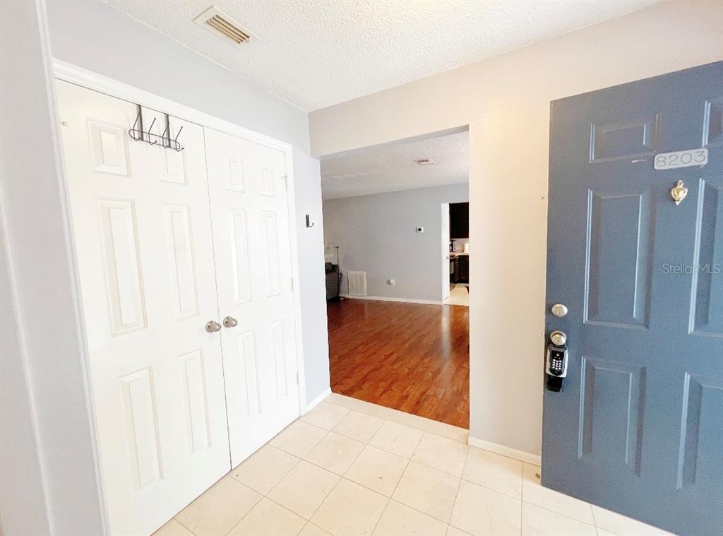 An entryway with tile flooring, a white closet, and a blue front door — 8203 OLYMPIA COURT UNIT 8203, LONGWOOD, FL