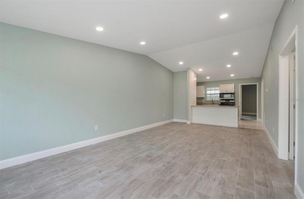 An open-concept living area features light green walls, recessed lighting, and wood-look tile flooring — 1184 WOODMAN WAY, ORLANDO, FL