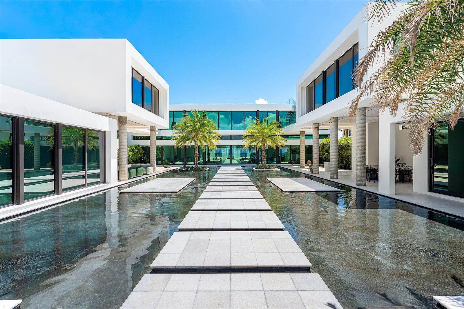 A modern white villa features a central reflecting pool with a stone walkway and palms — 6273 N Ocean Boulevard, Ocean Ridge FL 33435, OCEAN RIDGE, FL