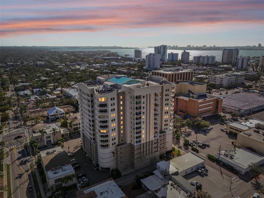 An aerial view shows a tall residential building surrounded by city streets and other structures — 1771 RINGLING BOULEVARD UNIT 1001, SARASOTA, FL