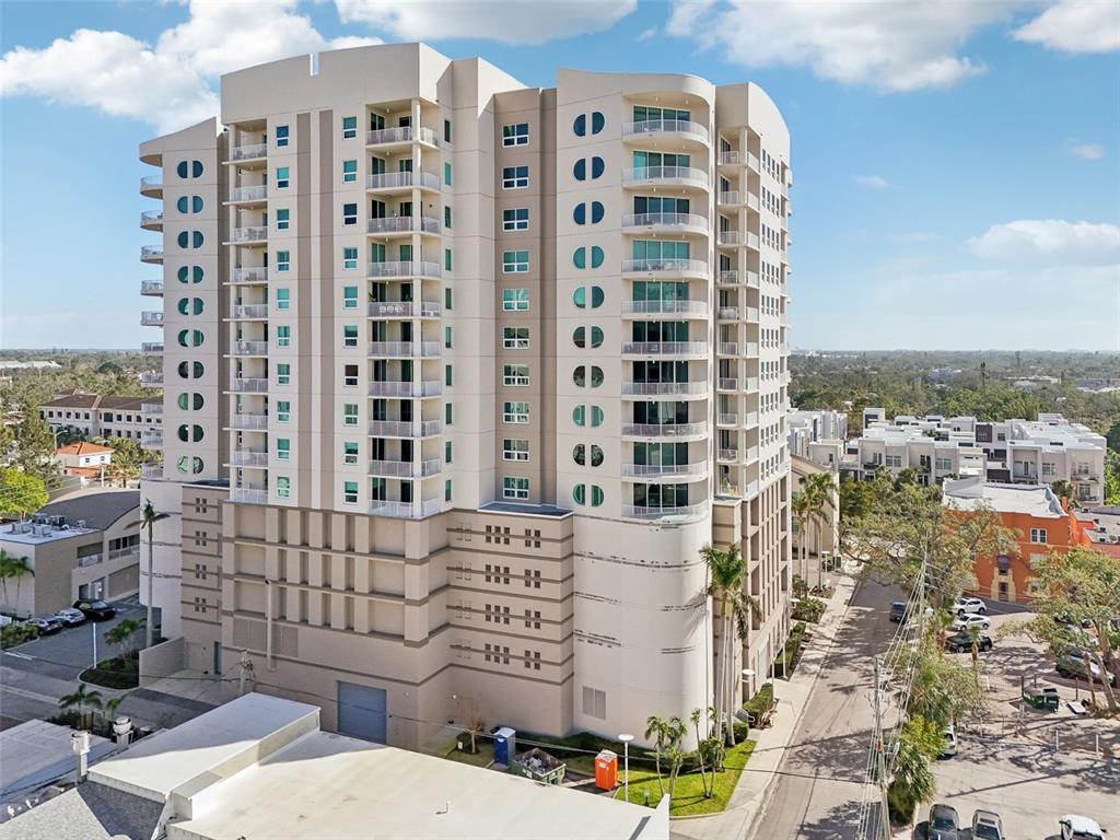 A curved balcony with stone pavers overlooks a city skyline under a blue sky — 1771 RINGLING BOULEVARD UNIT 1001, SARASOTA, FL