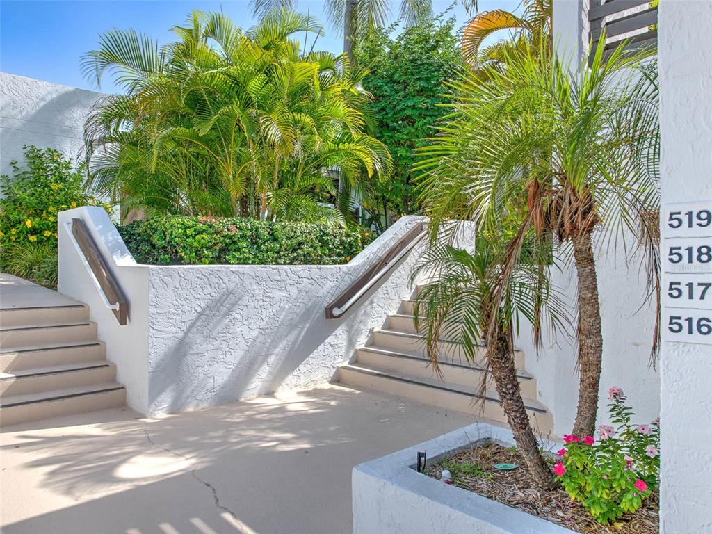 An exterior view shows two concrete staircases leading up to a building with unit numbers — 519 BAYPORT WAY UNIT 519, LONGBOAT KEY, FL