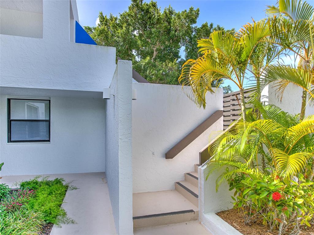 A white exterior wall features a window, a small staircase, and a nearby palm tree — 519 BAYPORT WAY UNIT 519, LONGBOAT KEY, FL