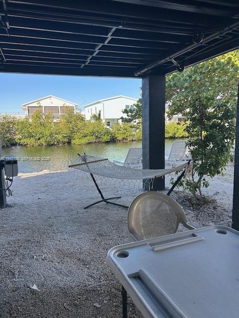 A covered patio features a hammock, outdoor chairs, and a table overlooking a canal — 74 Pelican Ln, Big Pine FL 33043, BIG PINE, FL