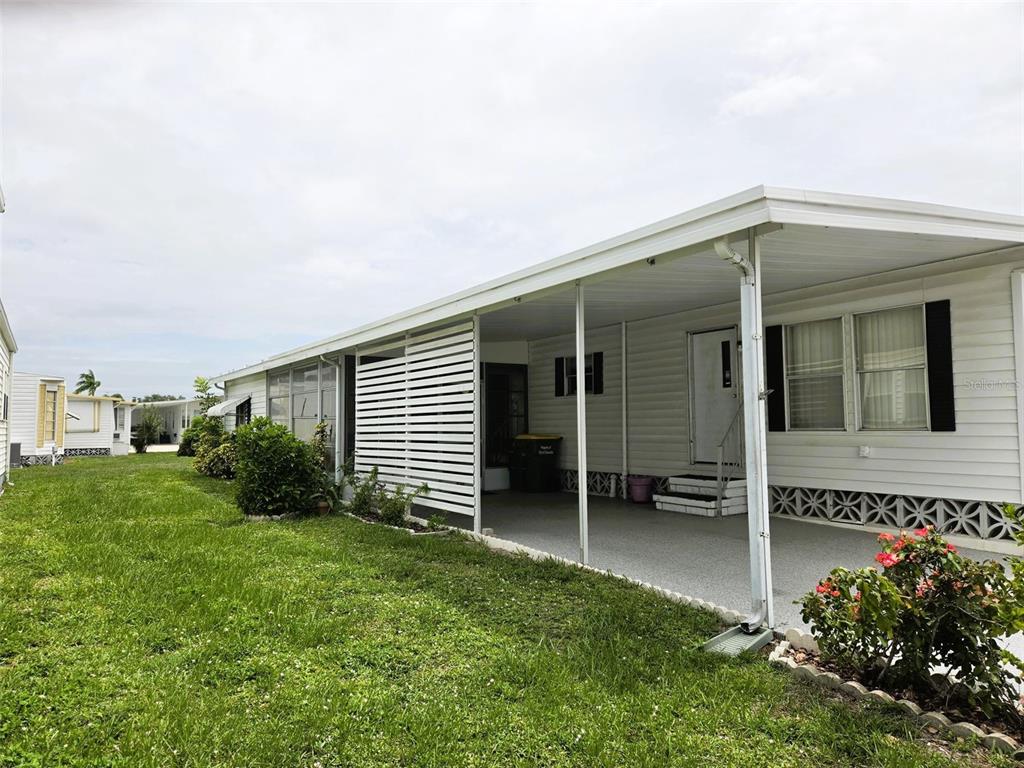 A mobile home exterior features a covered carport with white lattice siding and a lawn — 3329 OAKWOOD BOULEVARD S, SARASOTA, FL