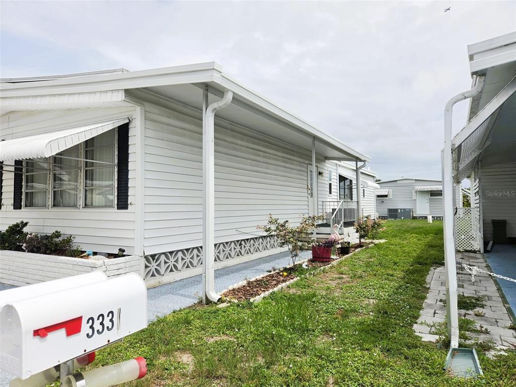 A white mobile home exterior features a mailbox in the foreground and a grassy yard — 3329 OAKWOOD BOULEVARD S, SARASOTA, FL