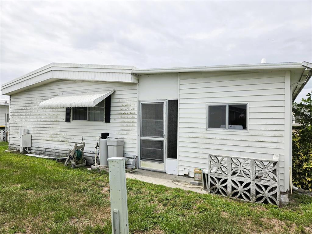 The exterior of a white mobile home features a screen door and decorative concrete blocks — 3329 OAKWOOD BOULEVARD S, SARASOTA, FL