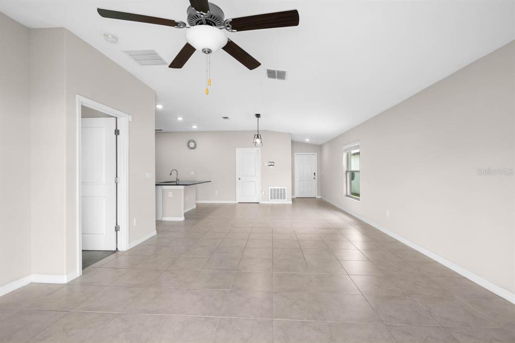 An open-concept living area features light tile flooring, a ceiling fan, and a kitchen island — 6823 KING CREEK DRIVE, SUN CITY CENTER, FL